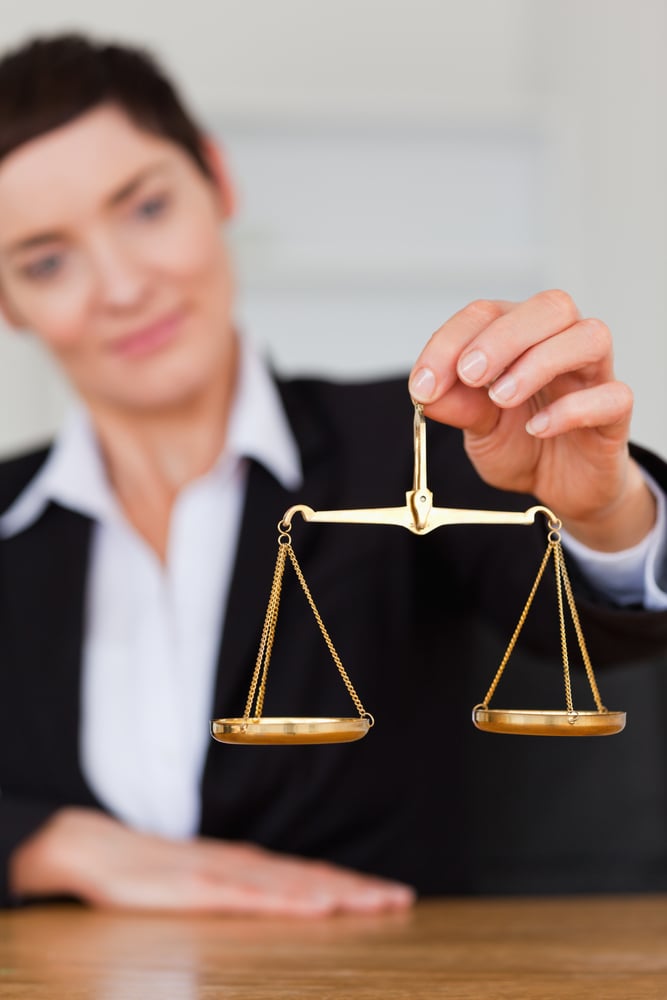 Serious woman holding the justice scale in her office-1